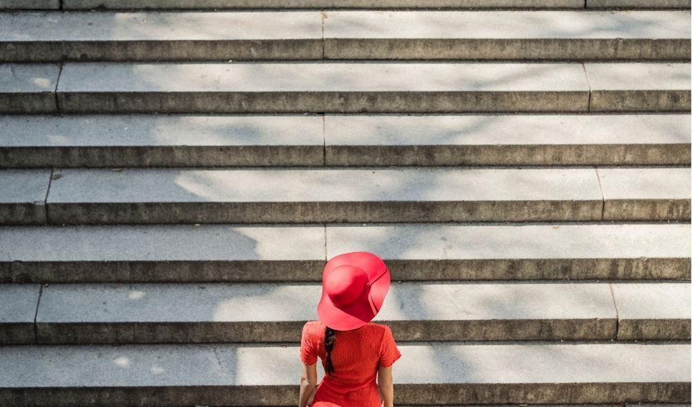 Mulher vestida de vermelho subindo escadas