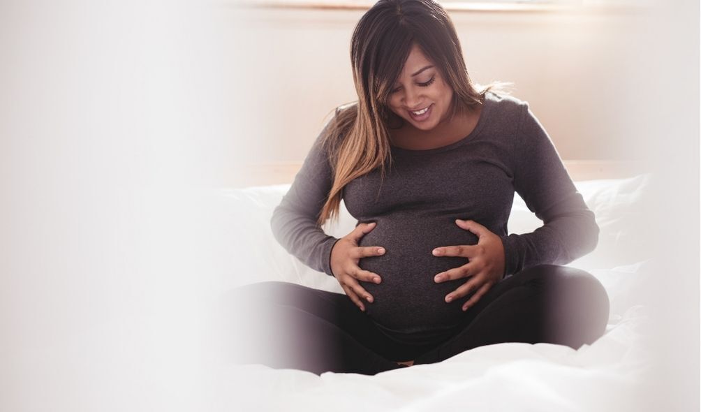 Mulher grávida sentada na cama