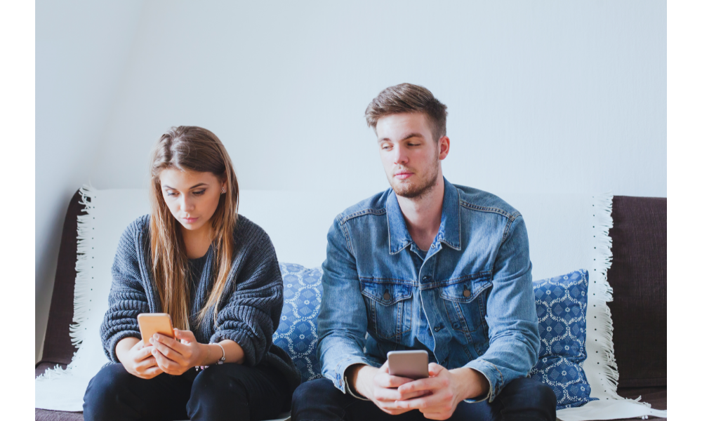 Homem ciumento olhando para o celular da namorada disfarçadamente.