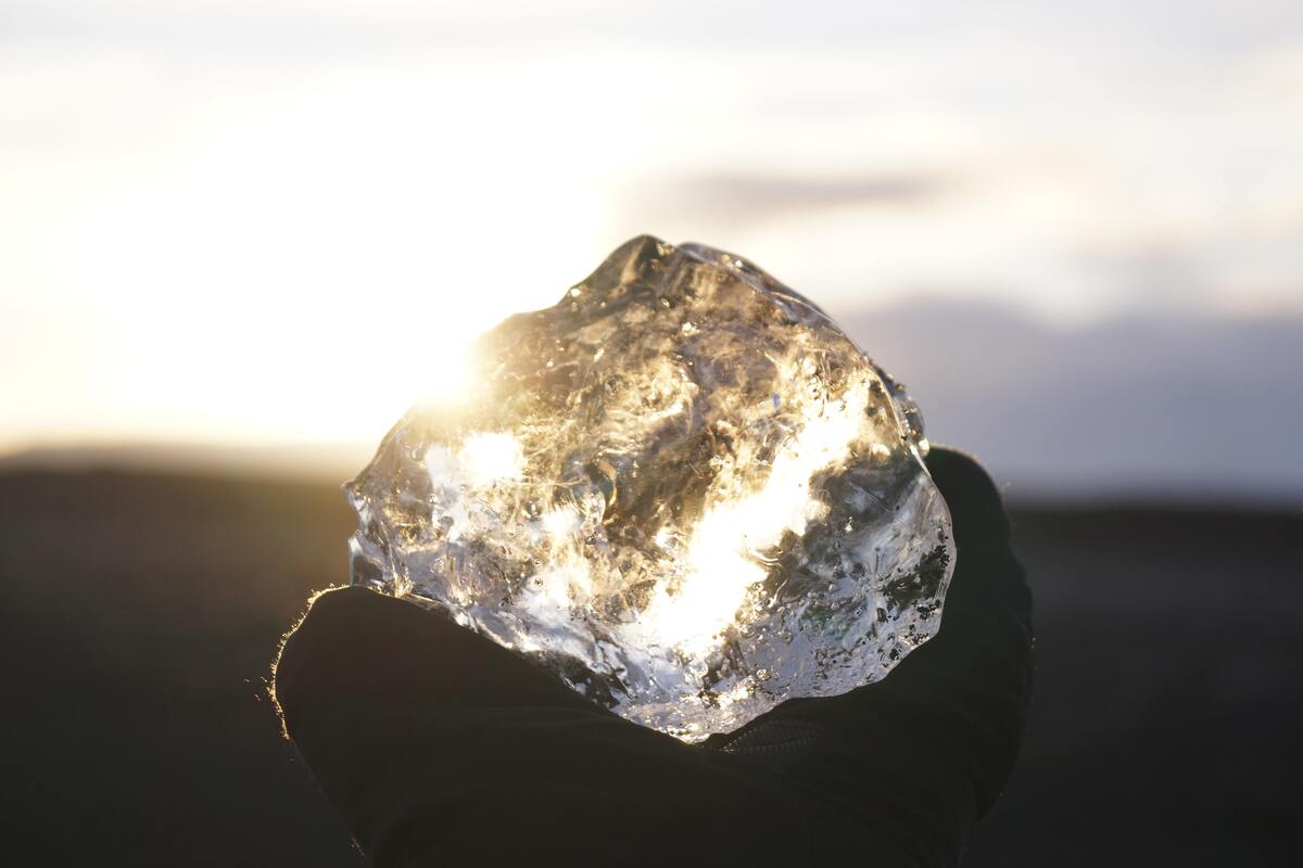 Mão segurando diamante brilhante na luz do sol