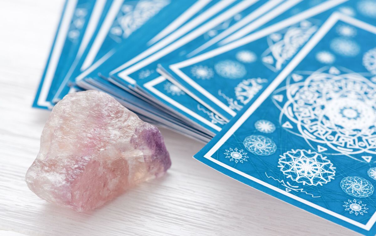 Cartas de Tarot com cristal ao lado.