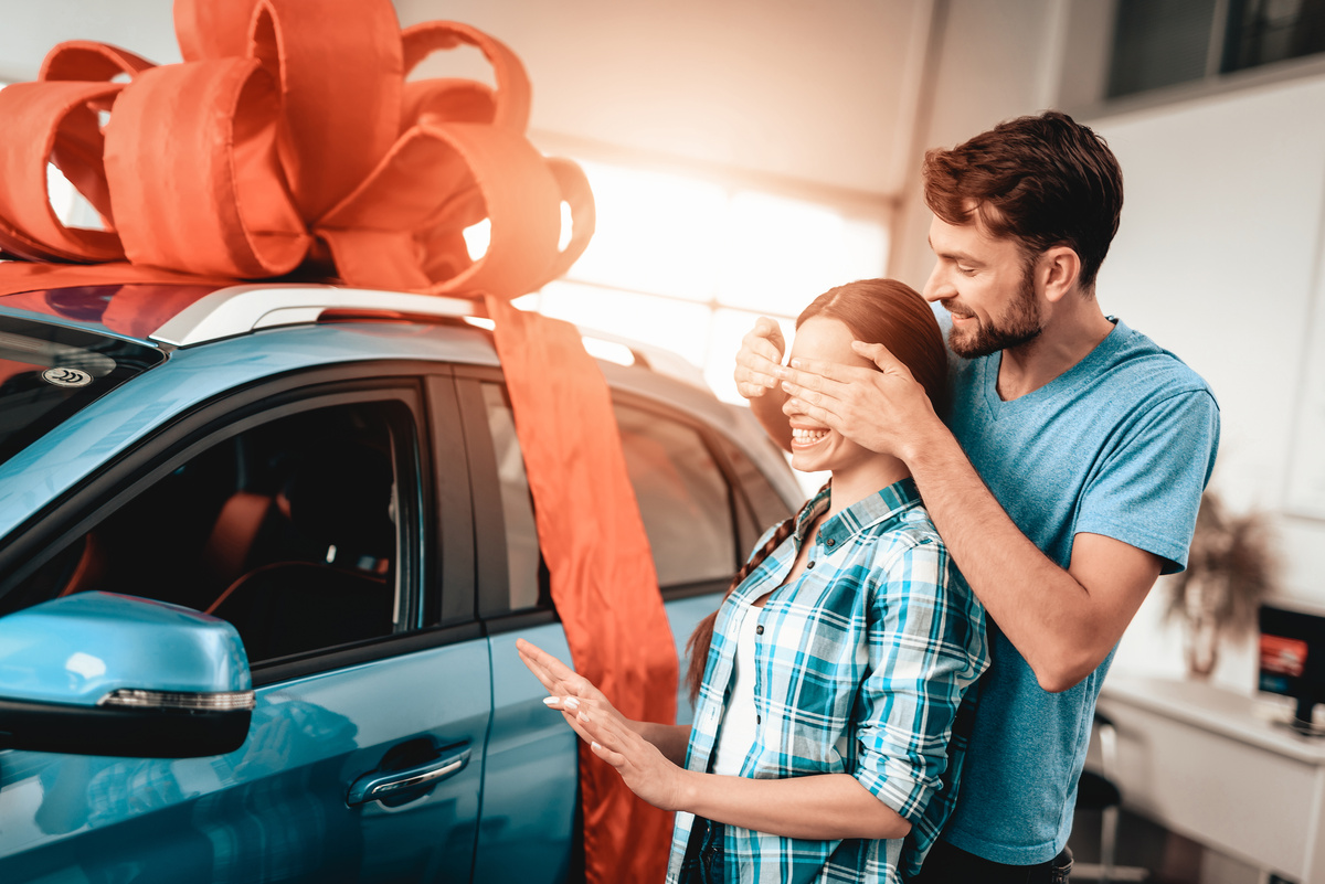 Homem presenteando mulher com carro novo.