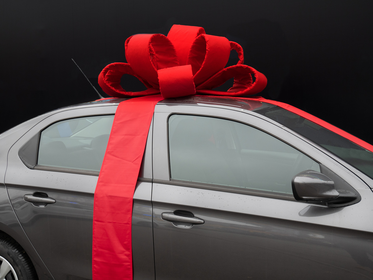 Carro novo preto com laço vermelho.