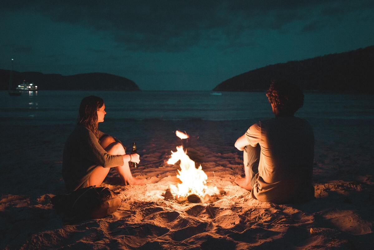 Casal ao lado de uma fogueira.