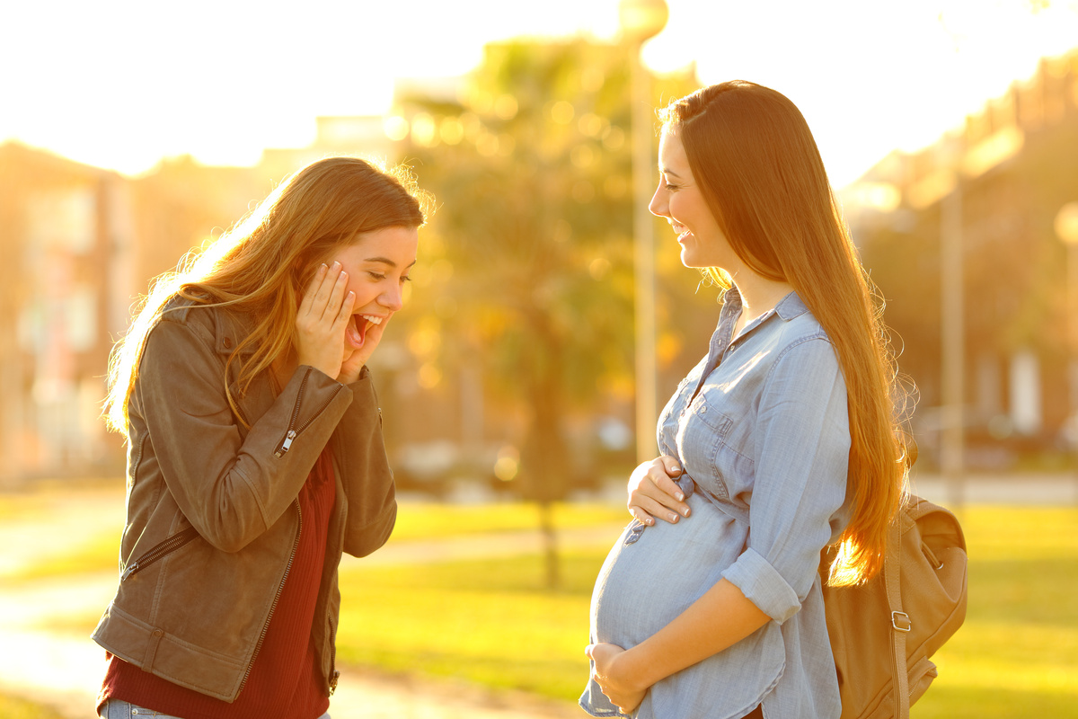 Mulher surpresa com barriga de grávida de pessoa conhecida. 