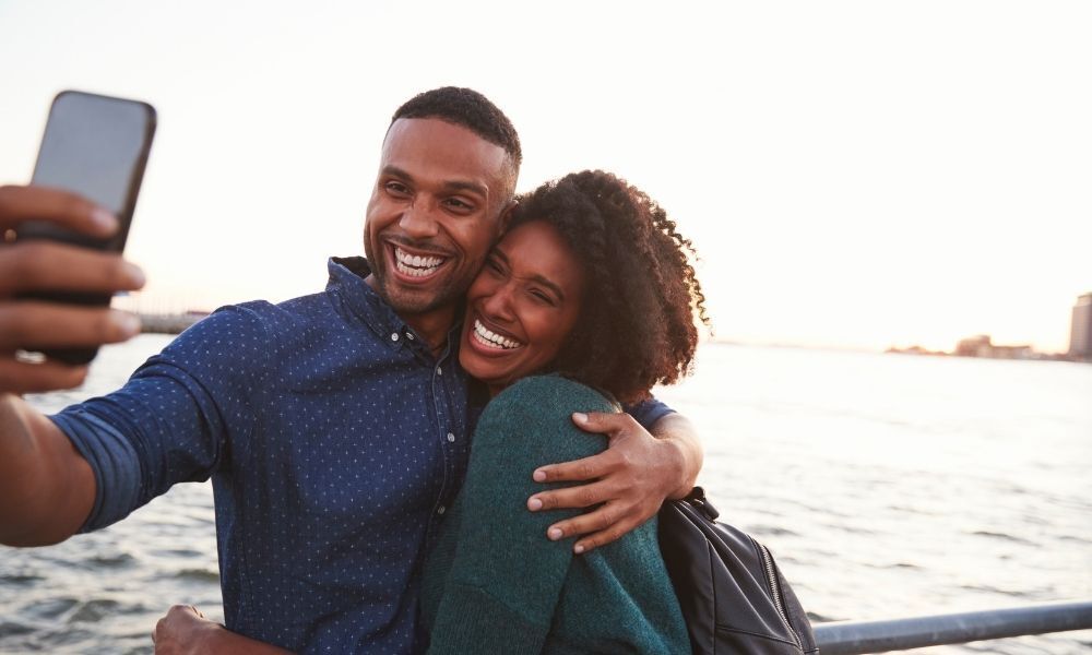 Casal de homem e mulher abraçados tirando foto.