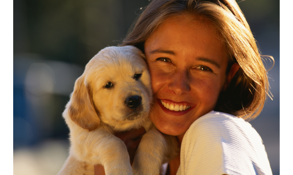 Mulher feliz e abraçando filhote de cachorro para tirar foto.