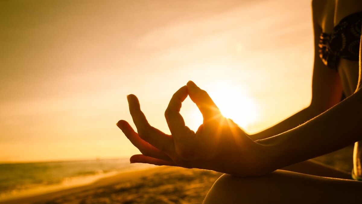 Pessoa meditando em uma praia.