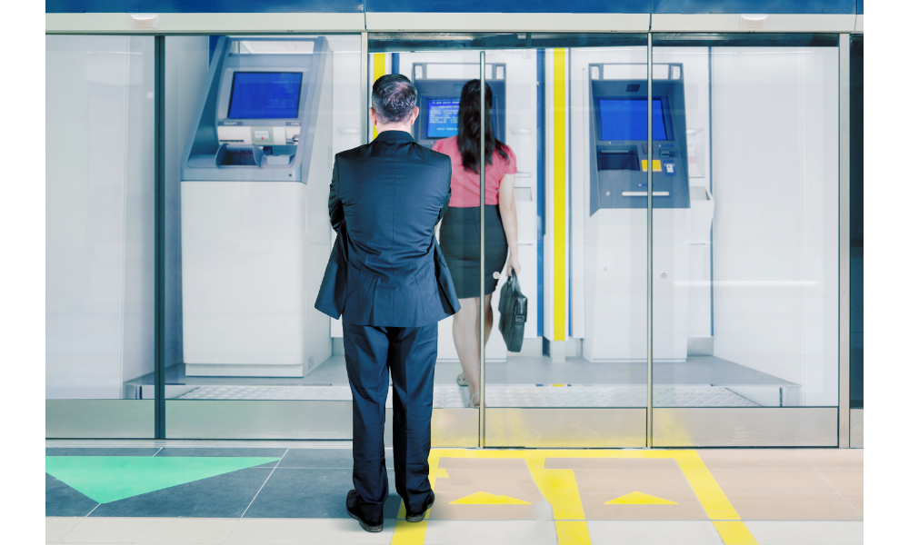 Homem esperando mulher no caixa eletrônico.