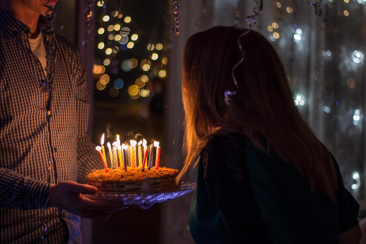 Menina assoprando bolo de aniversário.