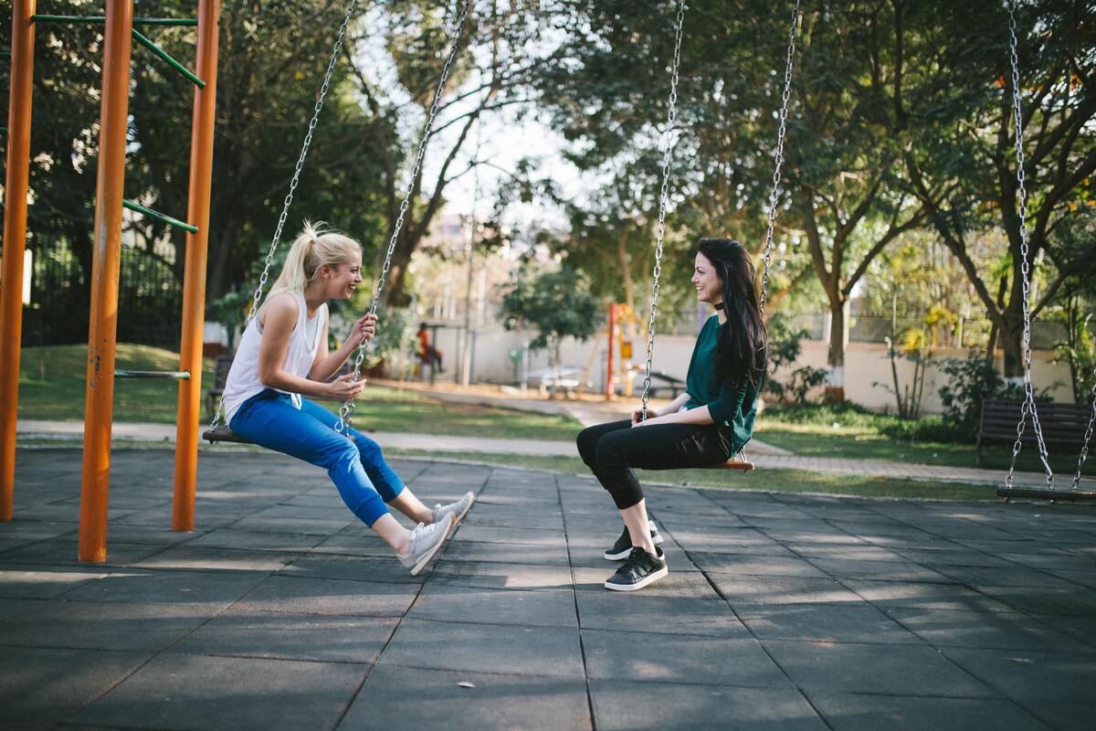 Duas mulheres brincando em balanços. 