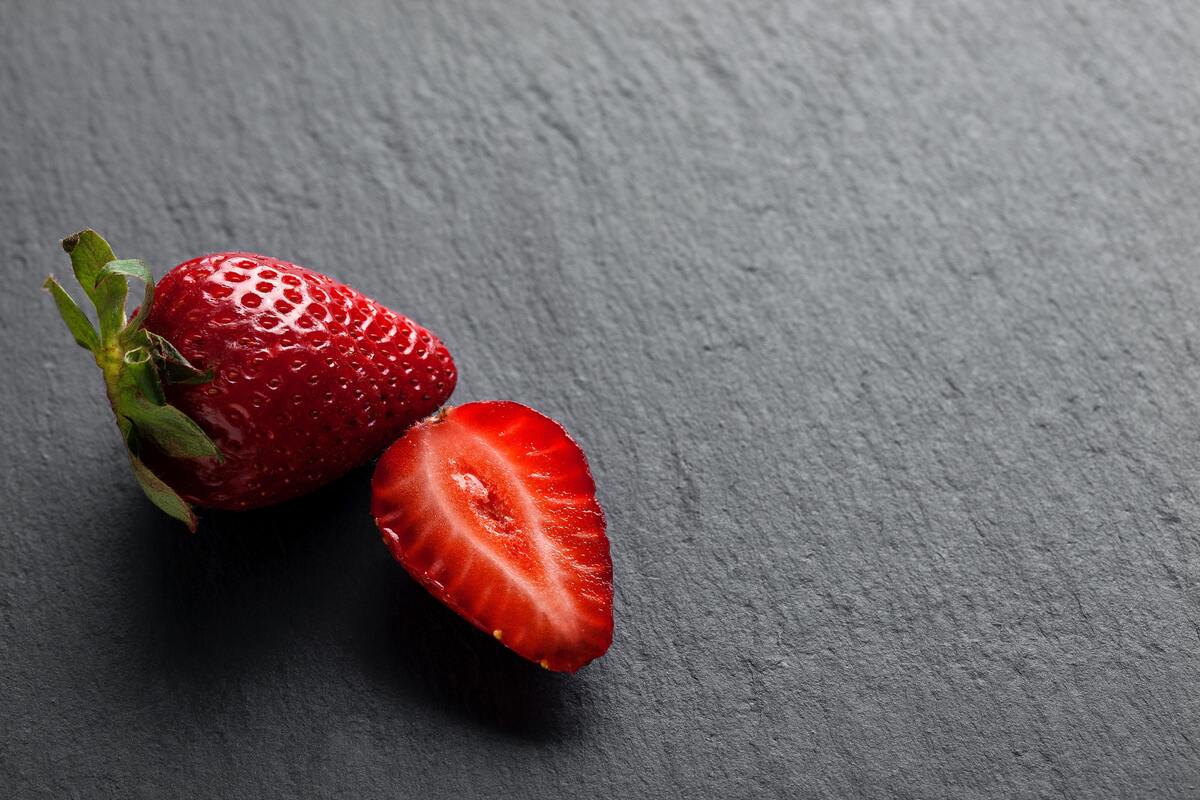 Um morando inteiro e uma metade de um morango em uma mesa.