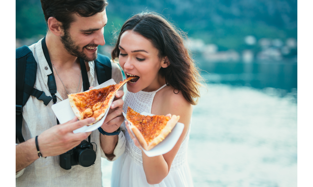 Casal comendo pizza junto.