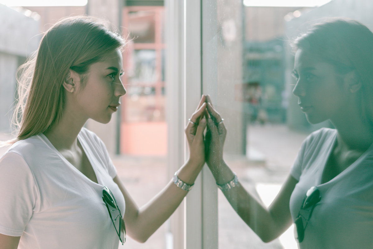 Mulher se olhando em reflexo no espelho