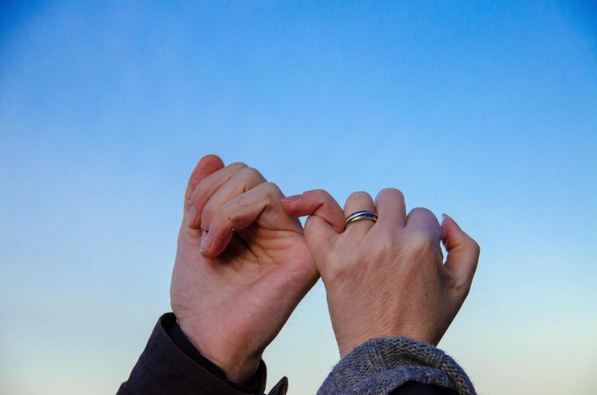 Casal com os mindinhos entrelaçados. 