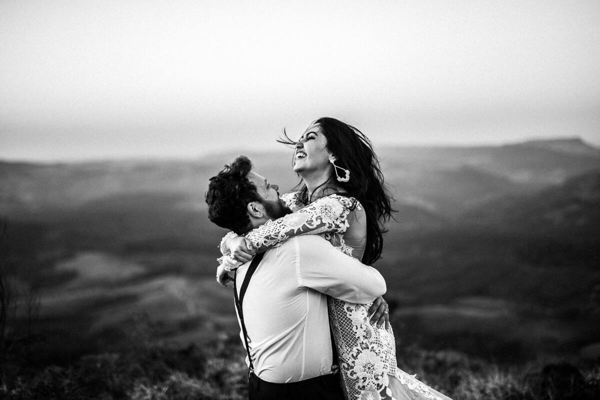 Casal se abraçando no topo de um morro.