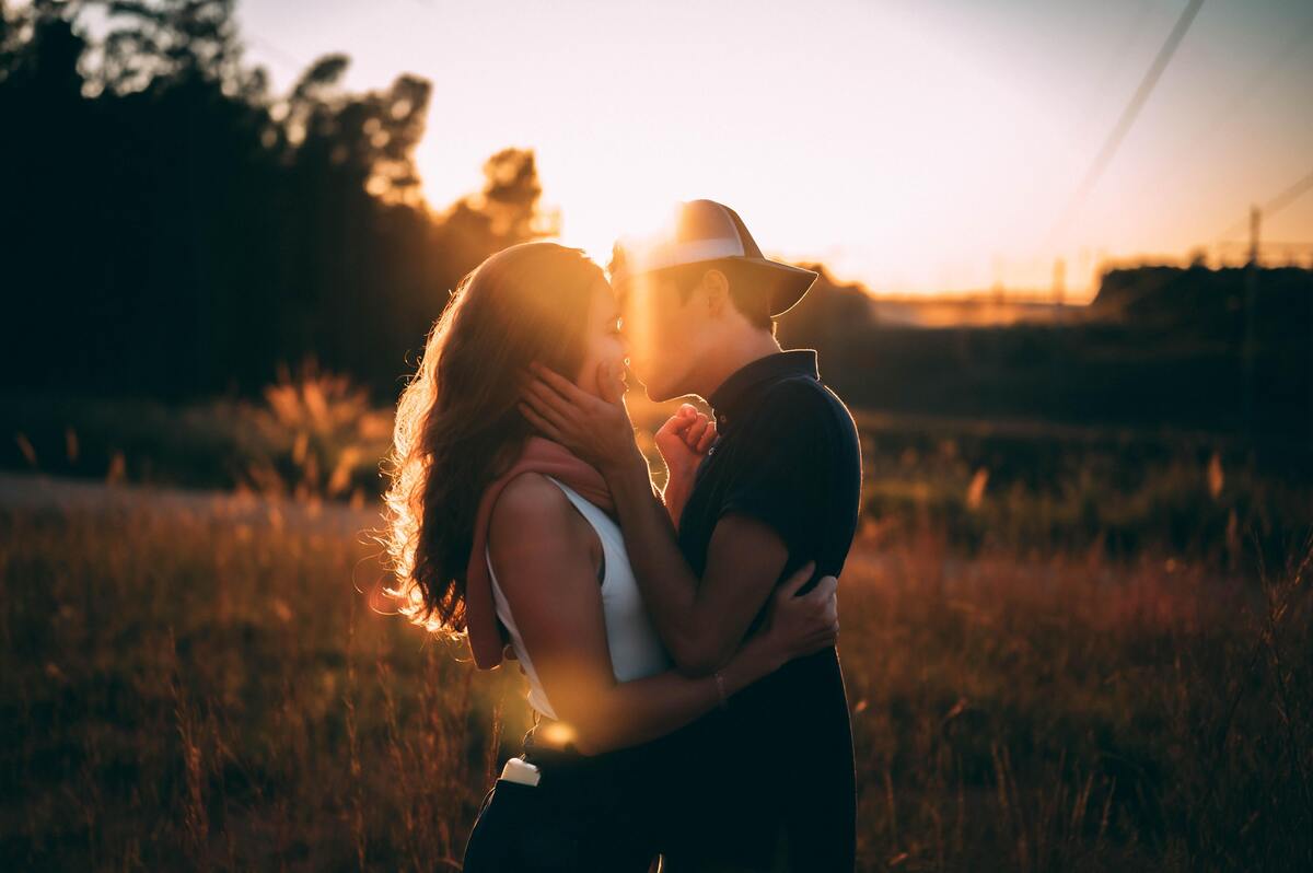 Casal se beijando contra o sol.