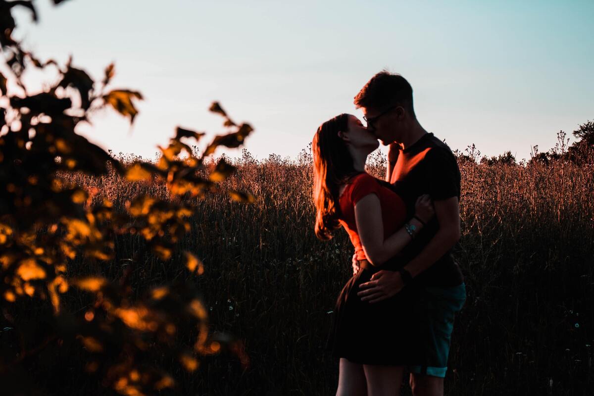 Casal se beijando em uma plantação.