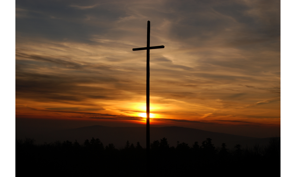 Cruz, fundo com pôr-do-sol.