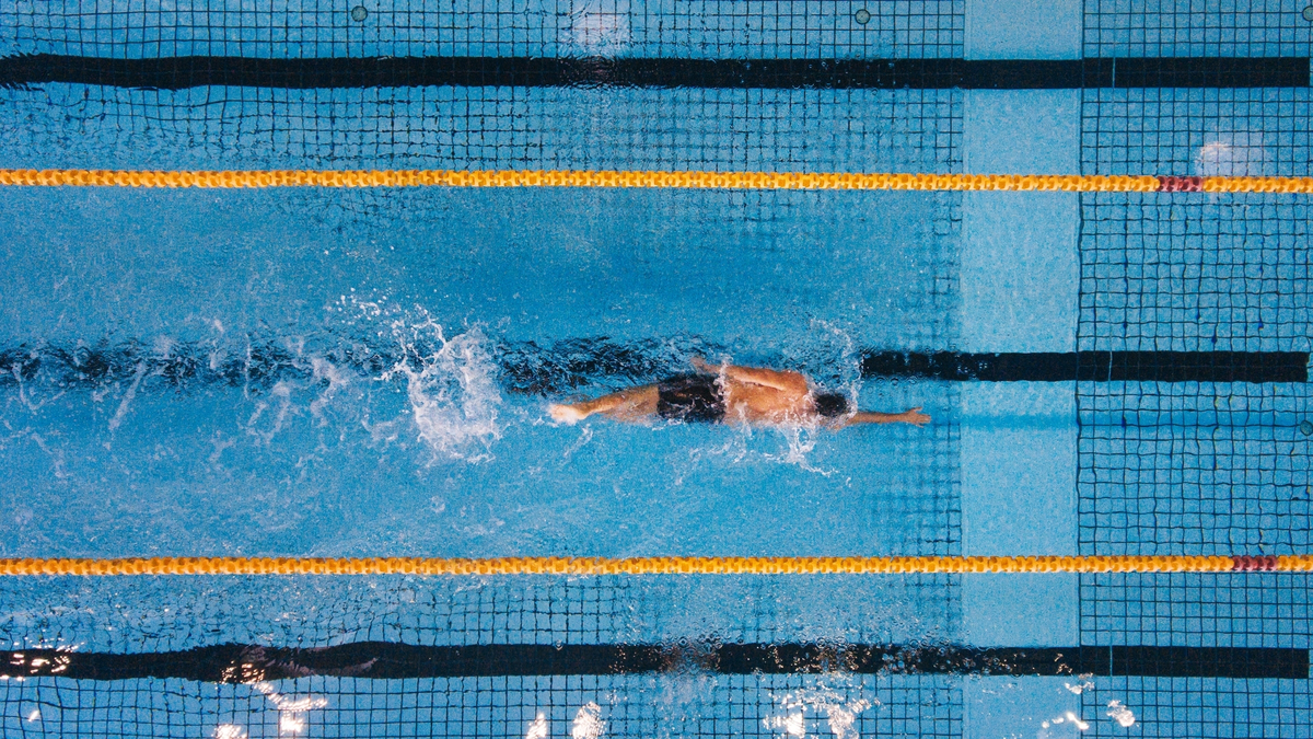 Homem nadando na piscina.