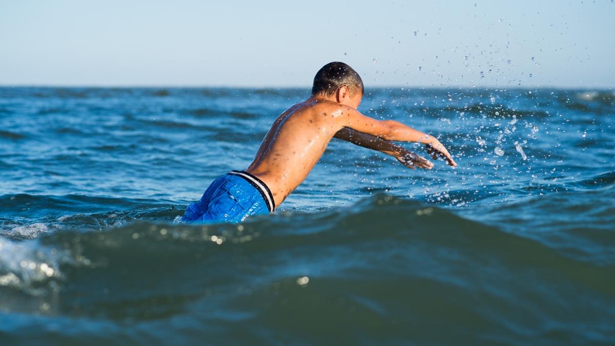 Menino nadando no mar.