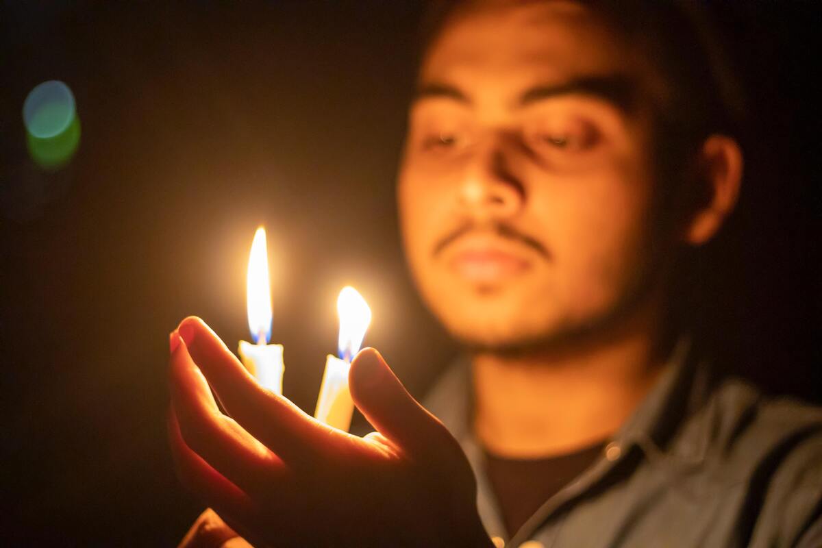 Homem segurando duas velas acesas. 