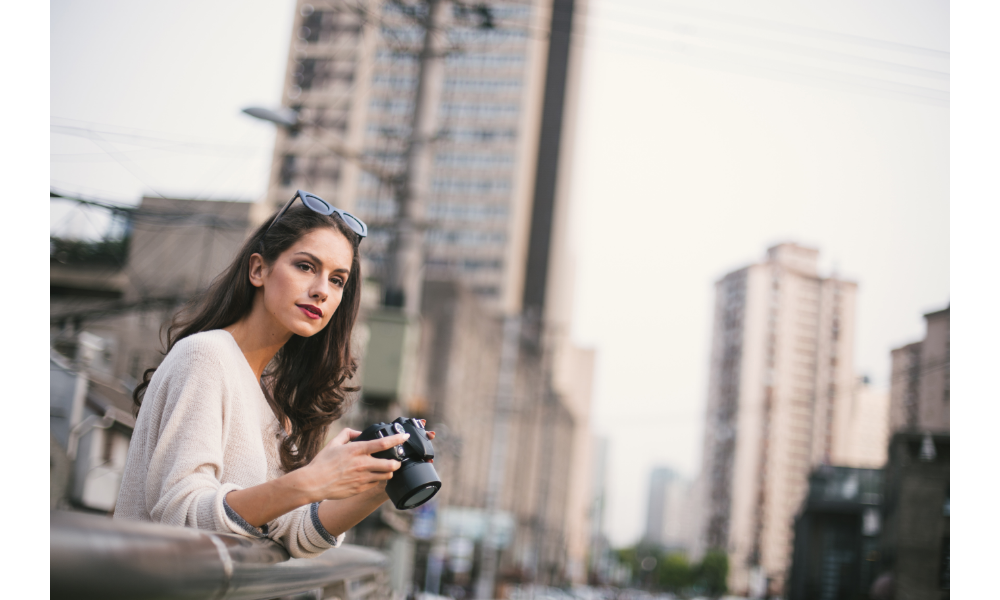 Mulher segurando uma câmera fotográfica.