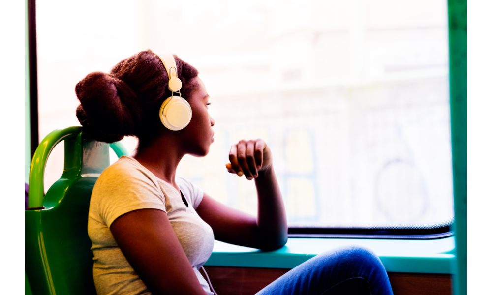 Mulher com fone de ouvido olhando a janela de um ônibus.