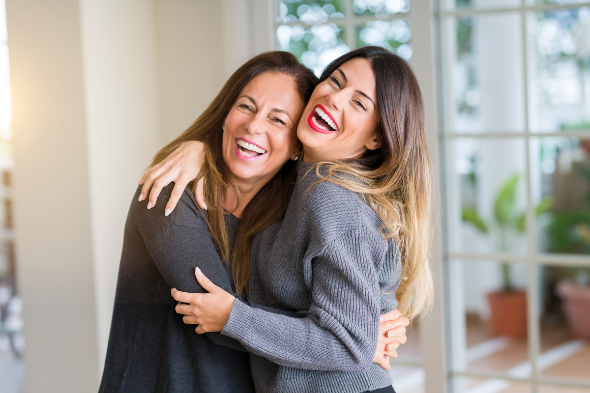 Mãe e filha abraçadas rindo