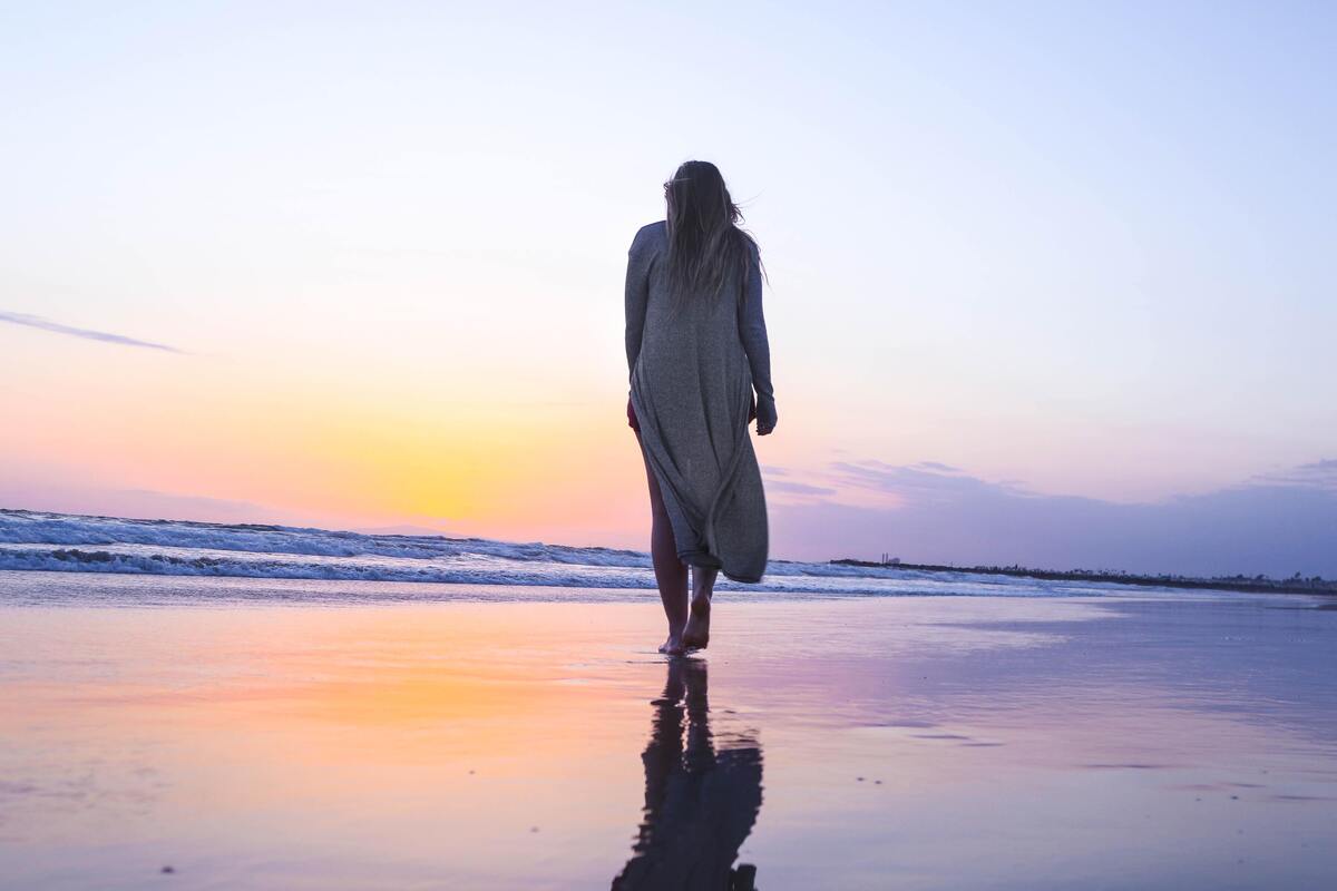 Mulher andando em uma praia.