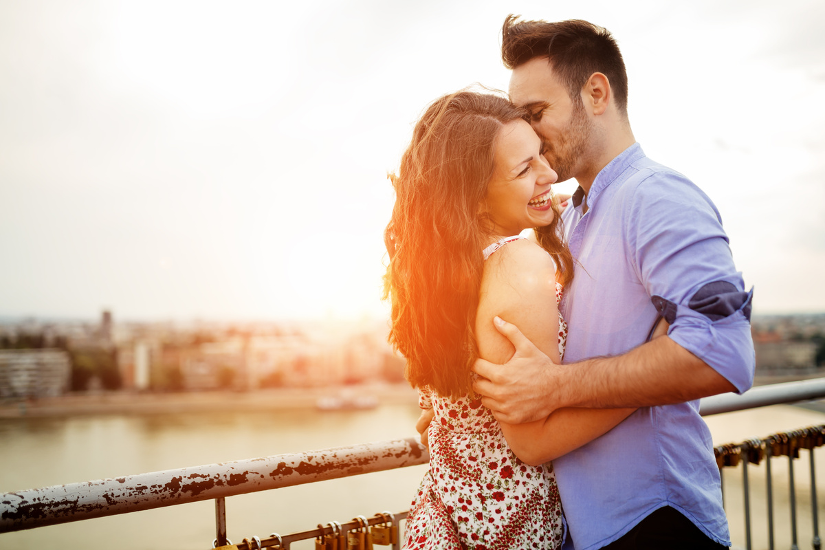 Casal sorrindo em uma ponte.