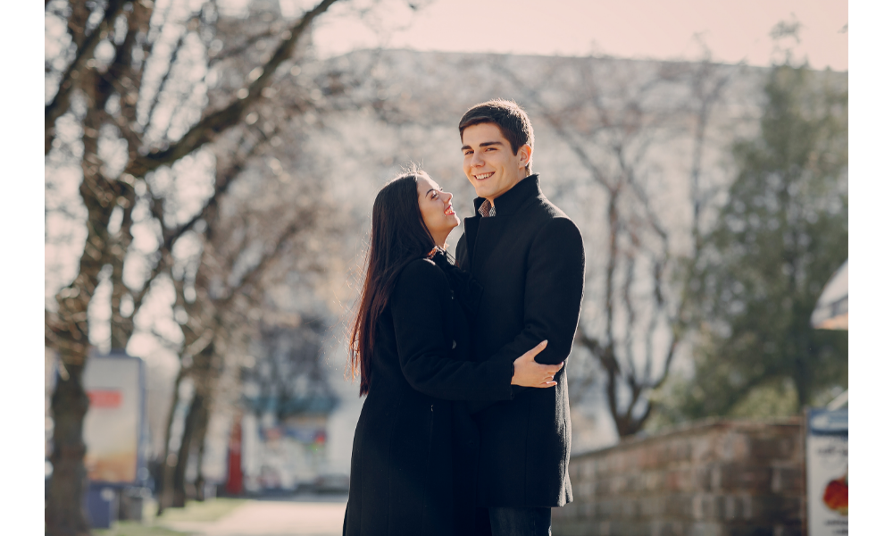 Casal vestido de preto se abraçando.