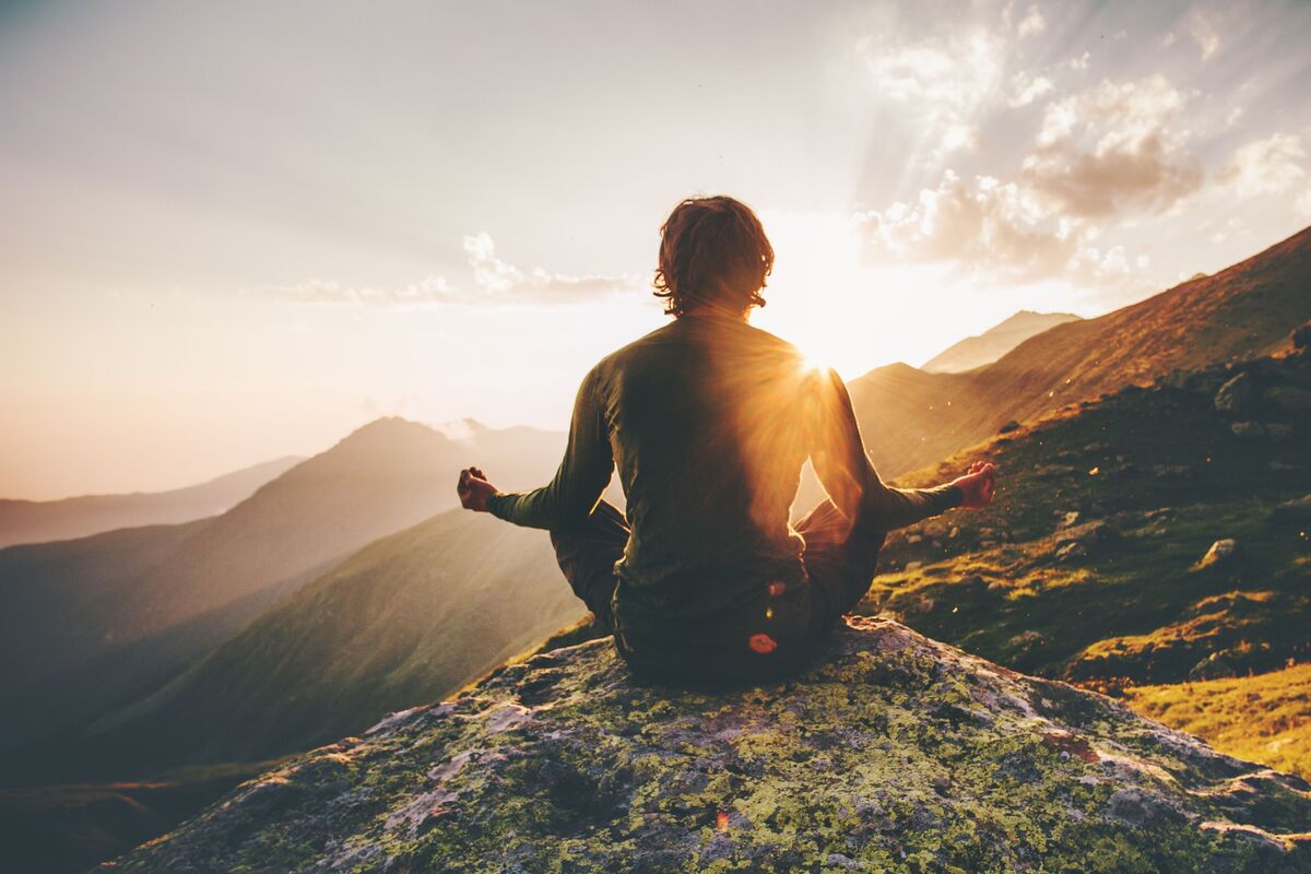 Homem meditando em montanhas.