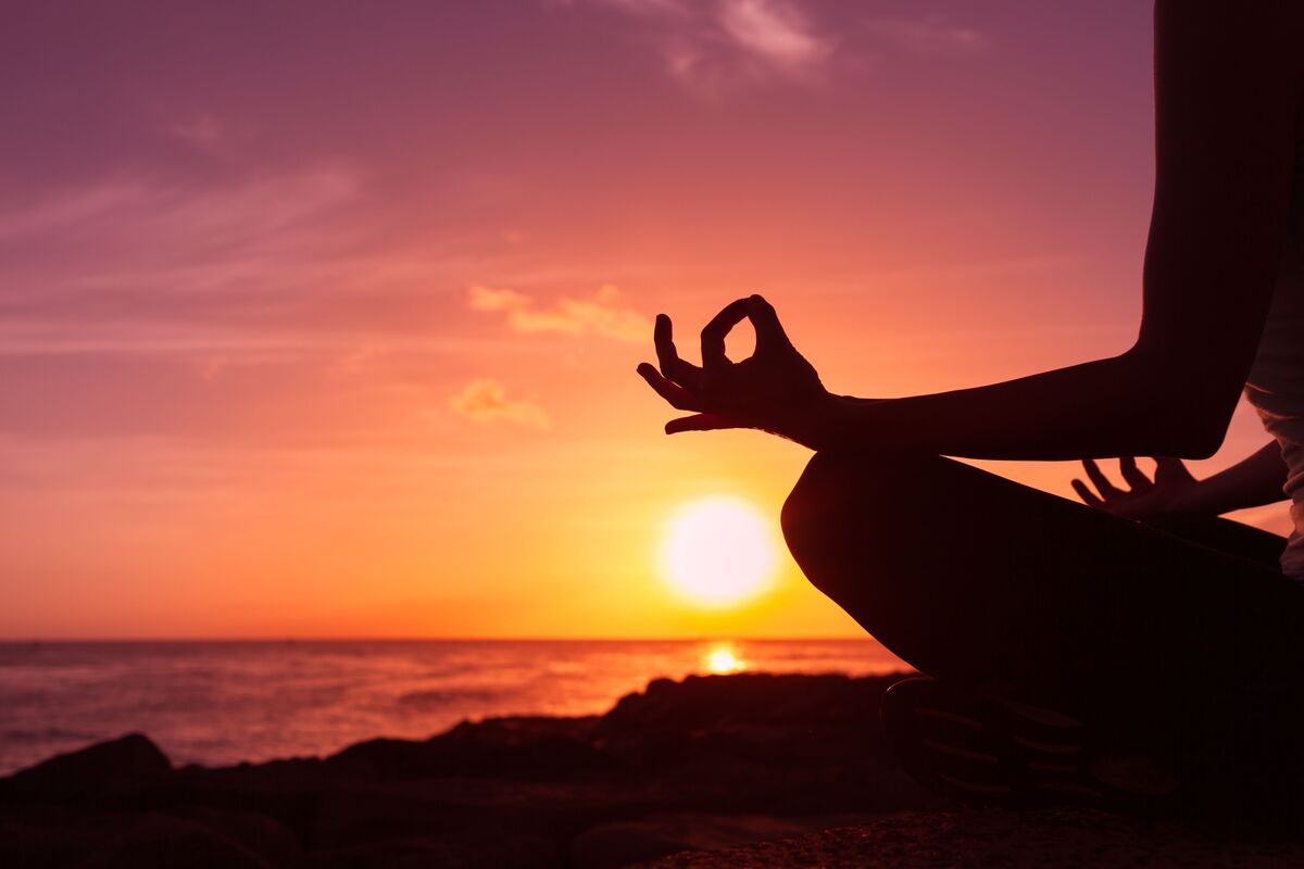 Pessoa meditando ao pôr do sol.