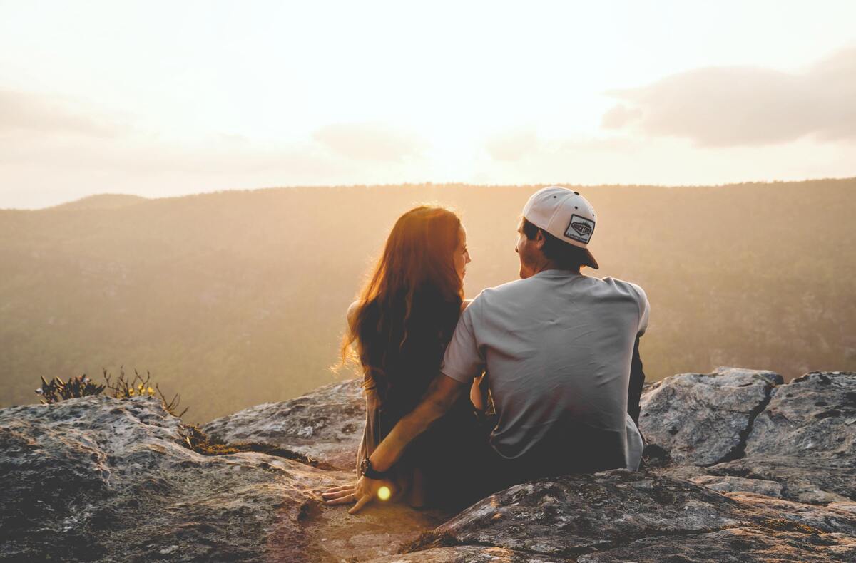 Casal se encarando, paisagem ao fundo.