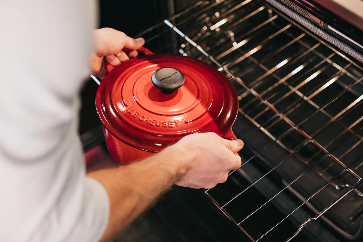 Homem colocando panela dentro do forno.