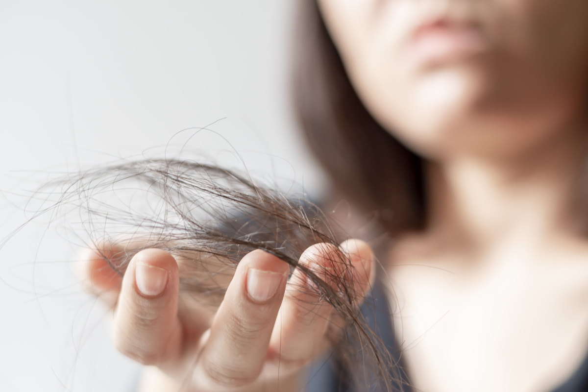 Mulher segurando um tufo de cabelo.