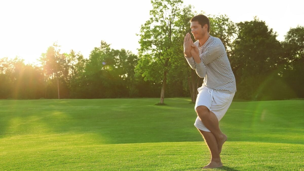 Homem praticando Yoga em um gramado.