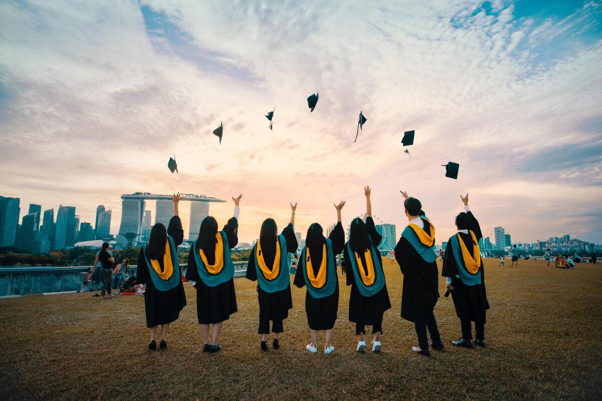 Pessoas jogando chapéu de formatura para o alto.