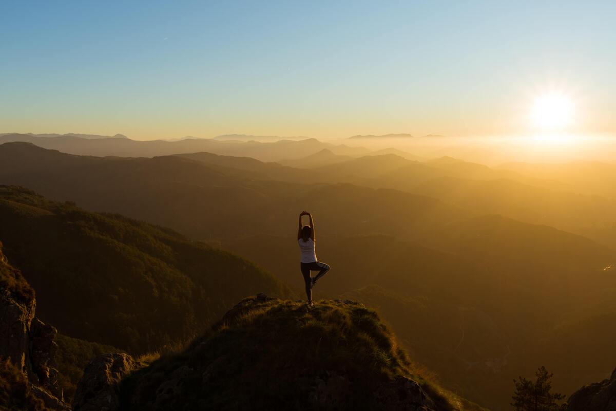 Mulher fazendo pose de yoga em cima de uma pedra.