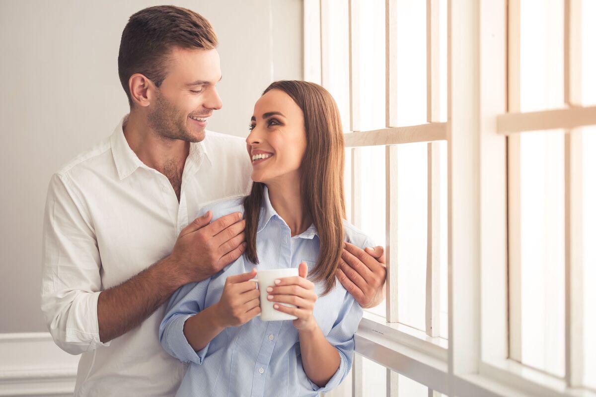 Casal abraçado e tomando café.