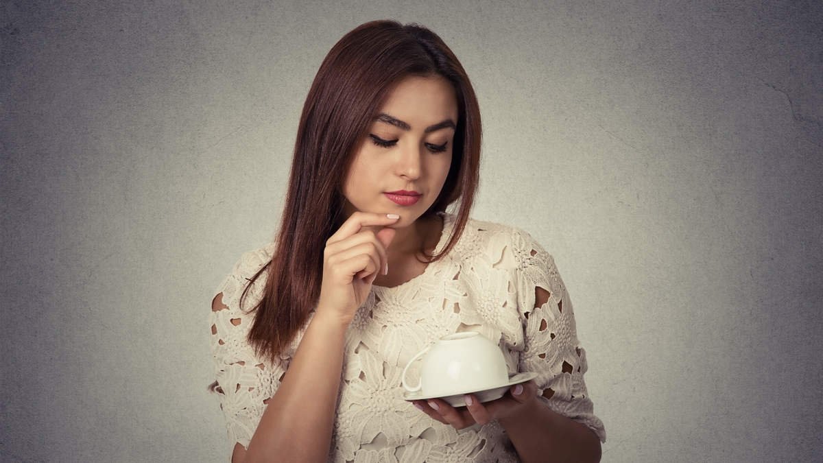 Mulher olhando para a xícara de café.