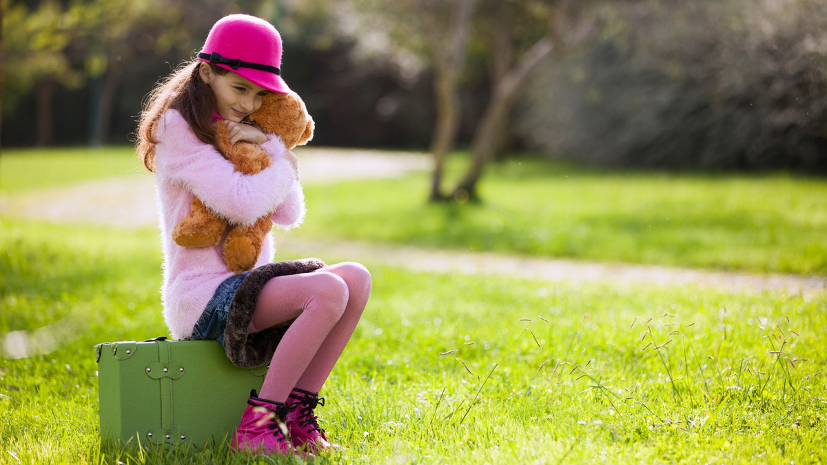 Menina abraçando o urso de pelúcia.