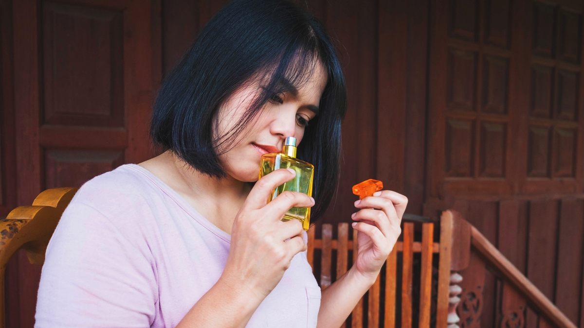 Mulher cheirando um perfume.