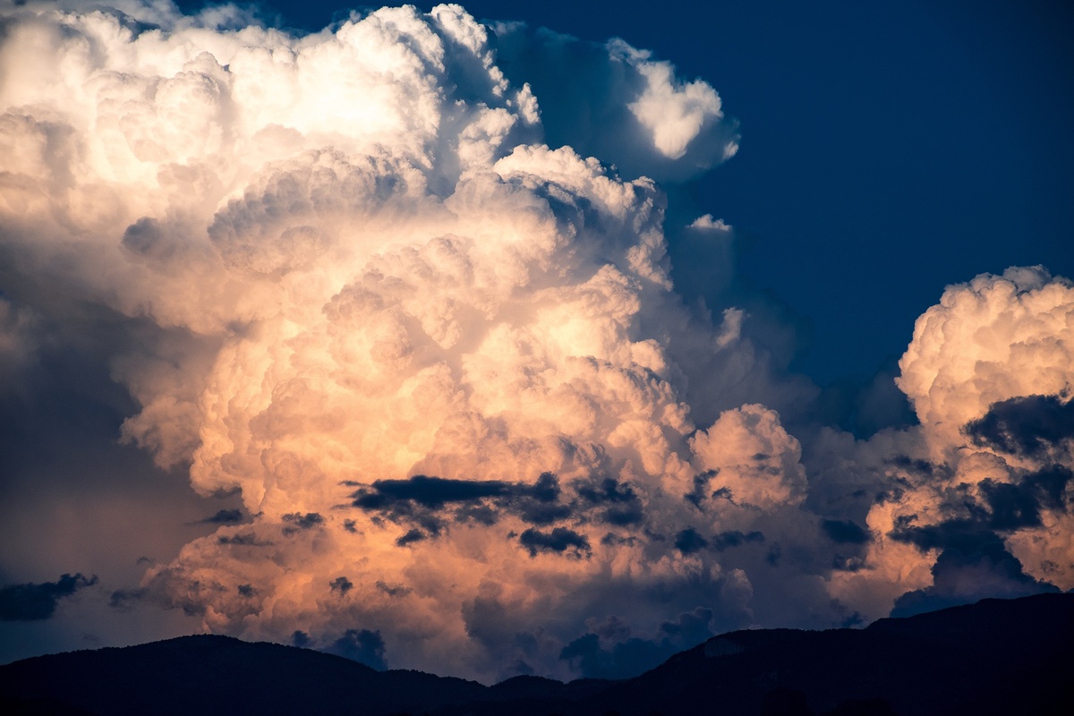 Nuvens brancas com tons avermelhados em céu escuro. 