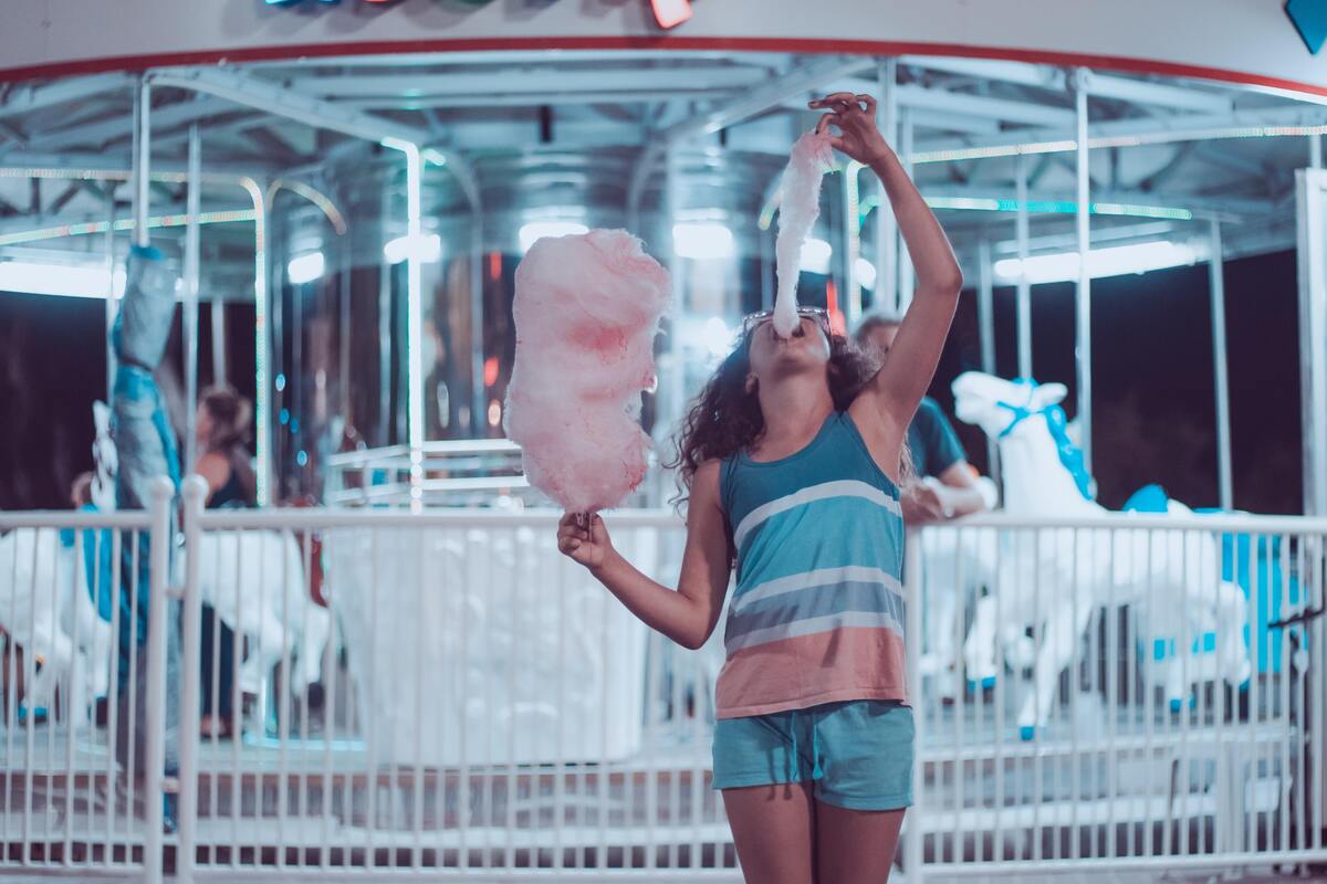 Menina comendo algodão doce.