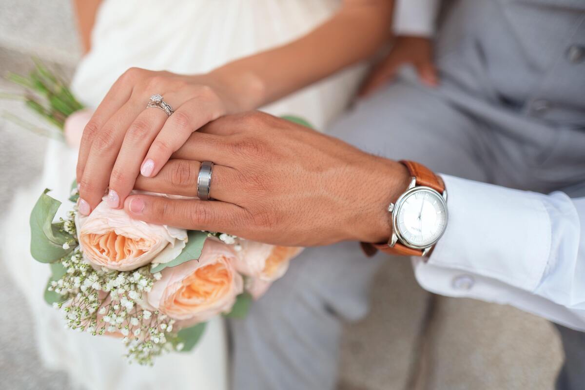 Mãos do casal com alianças.