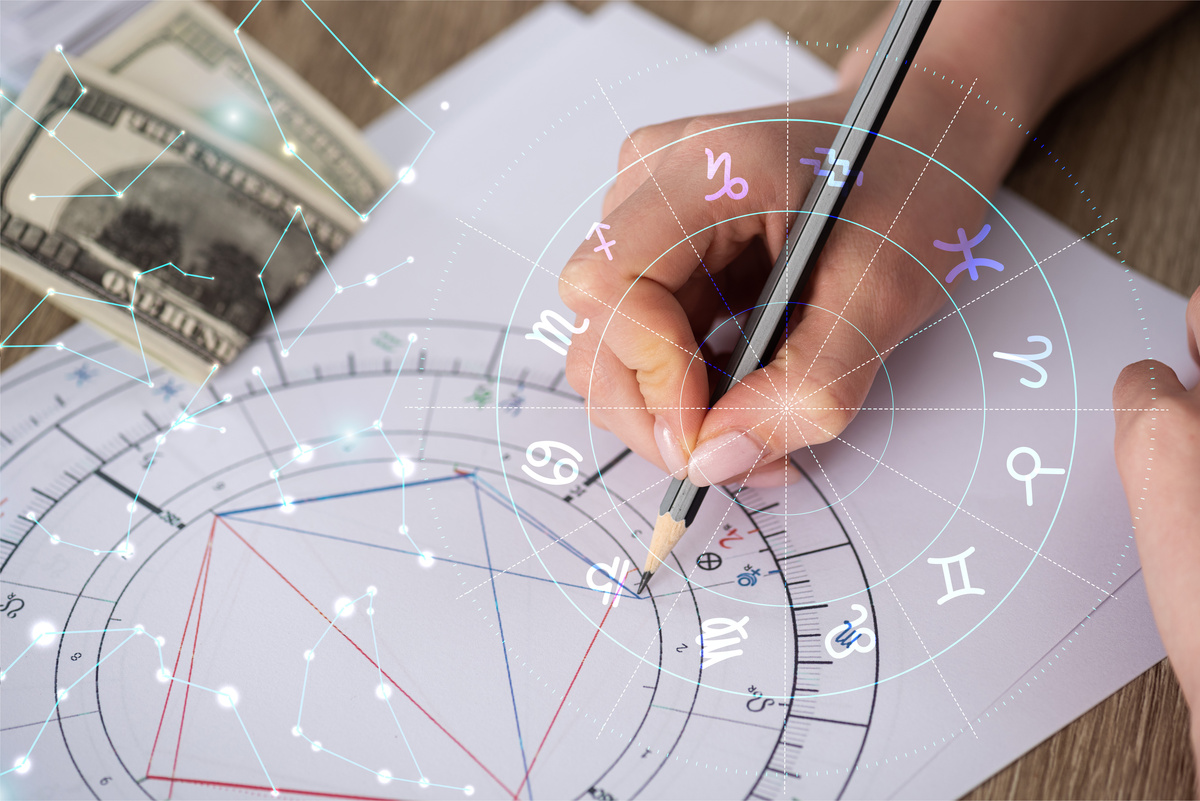 Pessoa fazendo mapa astral e notas de dólar ao lado