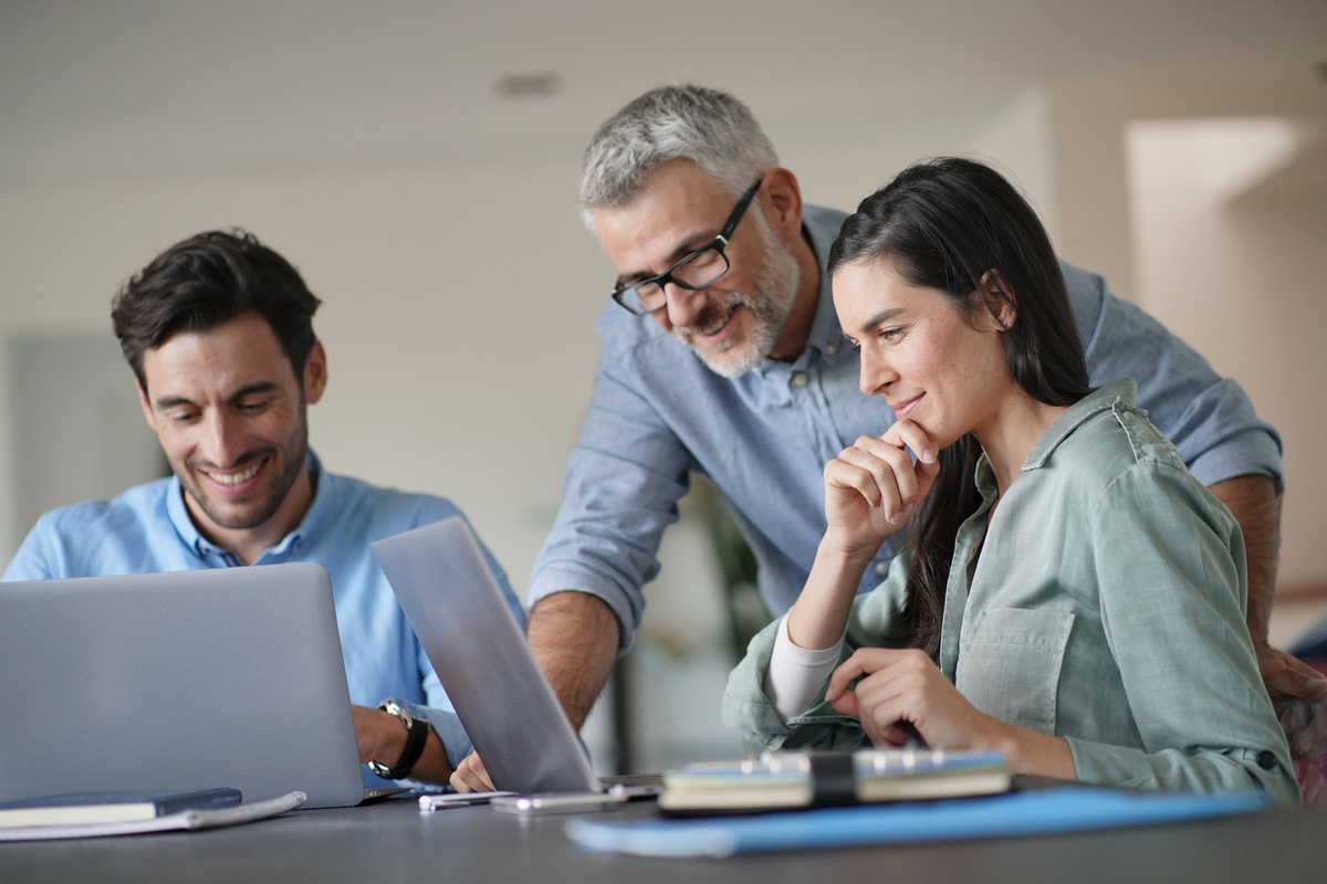 Patrão conversando e rindo com dois empregados mais jovens