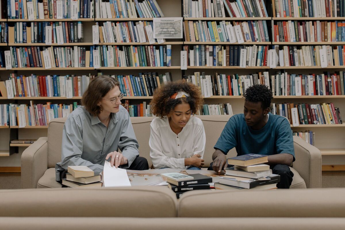 Grupo de amigos estudando em biblioteca.